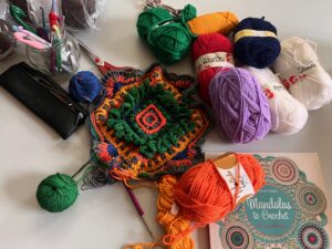 mandala crochet, crochet workshop, creative crafting, yarn art, handmade mandala, cozy studio, mindfulness, crafting community, crochet patterns, colorful designs, artistic crochet, crochet tools, relaxing atmosphere, DIY crafts, vibrant yarns.